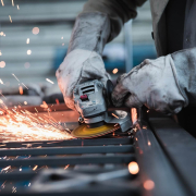 A metalworker grinds metal, producing a shower of sparks in the process