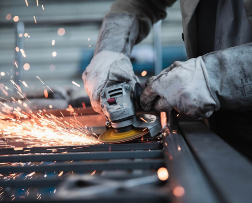 A metalworker grinds metal, producing a shower of sparks in the process