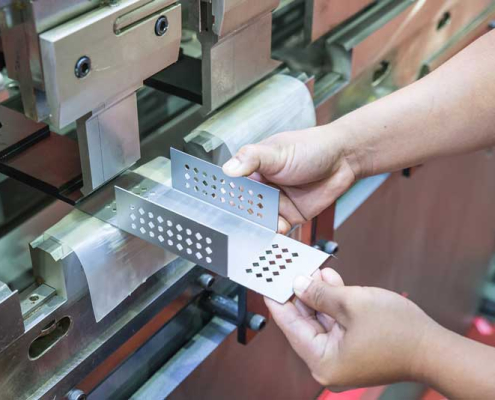 A person operates a metal cutting machine, skillfully shaping metal pieces