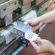A person operates a metal cutting machine, skillfully shaping metal pieces