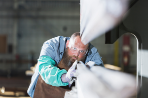 A worker preparing metal for welding in a factory