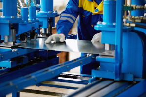 A worker operates a machine that processes and shapes metal in a manufacturing setting. 