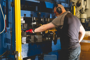 A factory worker operates a machine amid tools and machinery