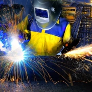 A worker welding a metal in industrial settings