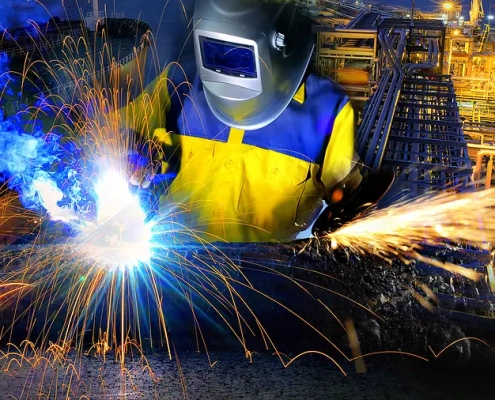 A worker welding a metal in industrial settings