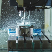 An industrial machine shapes a metal piece, utilizing water in the manufacturing process