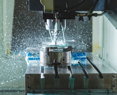 An industrial machine shapes a metal piece, utilizing water in the manufacturing process