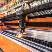 In a factory, a laser machine is actively cutting steel, highlighting the manufacturing process and machinery in action.