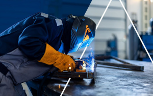  A close-up of a TIG welding process in an industrial environment, showcasing bright sparks and a welder's focused expression.