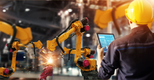 A man in a hard hat holds a tablet, overseeing metal fabrication processes on a construction site. 