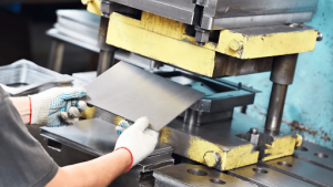 a metal presswork supplier shaping a metal sheet on a workbench, focused on their task in a well-lit industrial environment. 