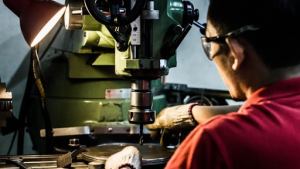 A factory worker is engaged in operating a machine, surrounded by various tools and machinery