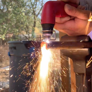 A person lights a fire using a plasma cutting, casting a warm glow in the surrounding area. 
