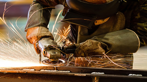 A man wearing protective gear is welding metal pieces together