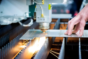 An individual uses a laser cutting machine, skillfully guiding the tool to cut detailed patterns