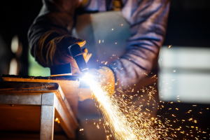 A welder in action, doing fabrication by joining metal pieces together with a welding torch