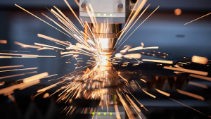 A metal-cutting machine produces bright sparks as it slices through metal material