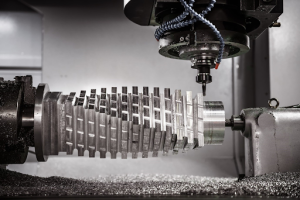 A CNC milling machine operates on a large metal object, shaping it with precision