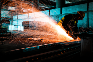 A man welding metal in a factory, sparks flying 