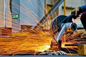 A man uses a grinder for metal presswork 