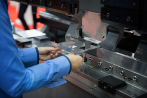 A factory worker operating a metal presswork machine